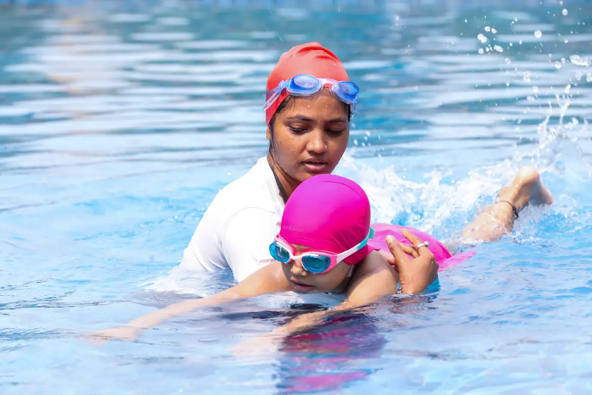 Schwimmlehrerin hält ein Kind beim Schwimmkurs im Becken