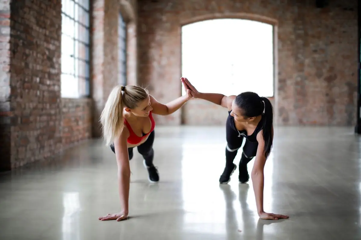 Zwei Frauen klatschen sich beim Training im Fitnessstudio ab