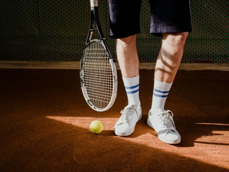 Tennisspieler mit Schläger und Ball auf dem Sandplatz
