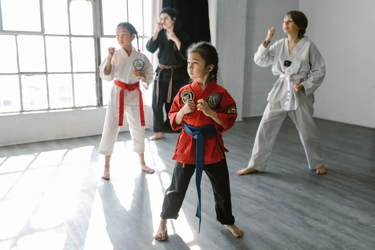 Kinder im Kampfsporttraining mit Trainerin in einem hellen Dojo