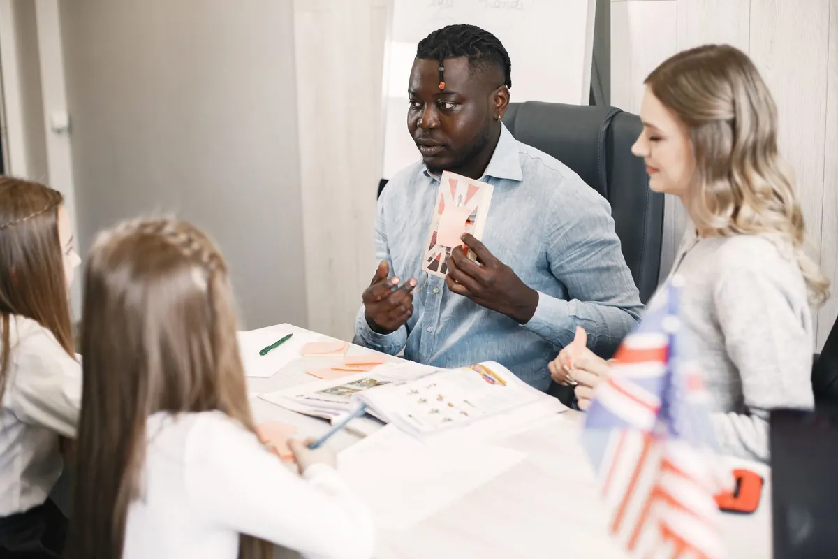 Lehrer übt mit einer Gruppe am Tisch Englisch mit Bildkarten