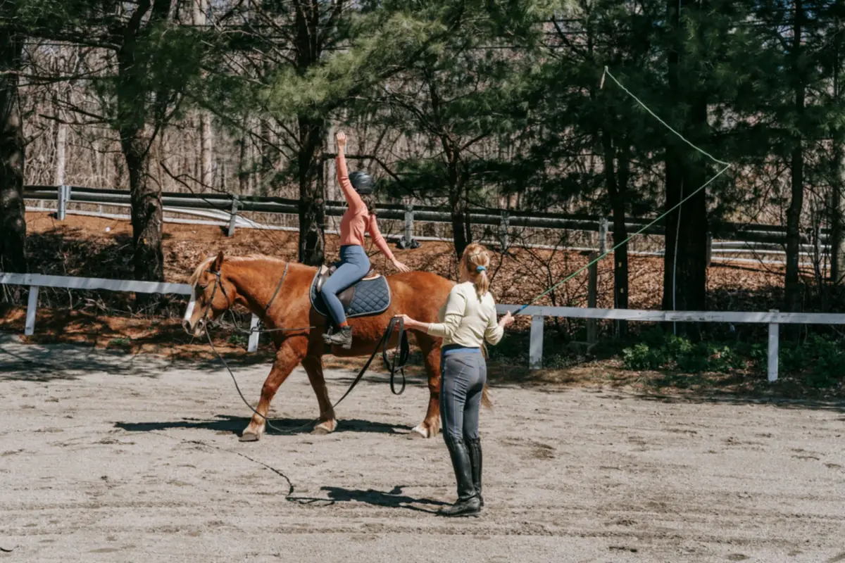 Reitstunde am Reitplatz: Reitlehrerin an der Longe, Reiterin auf dem Pferd