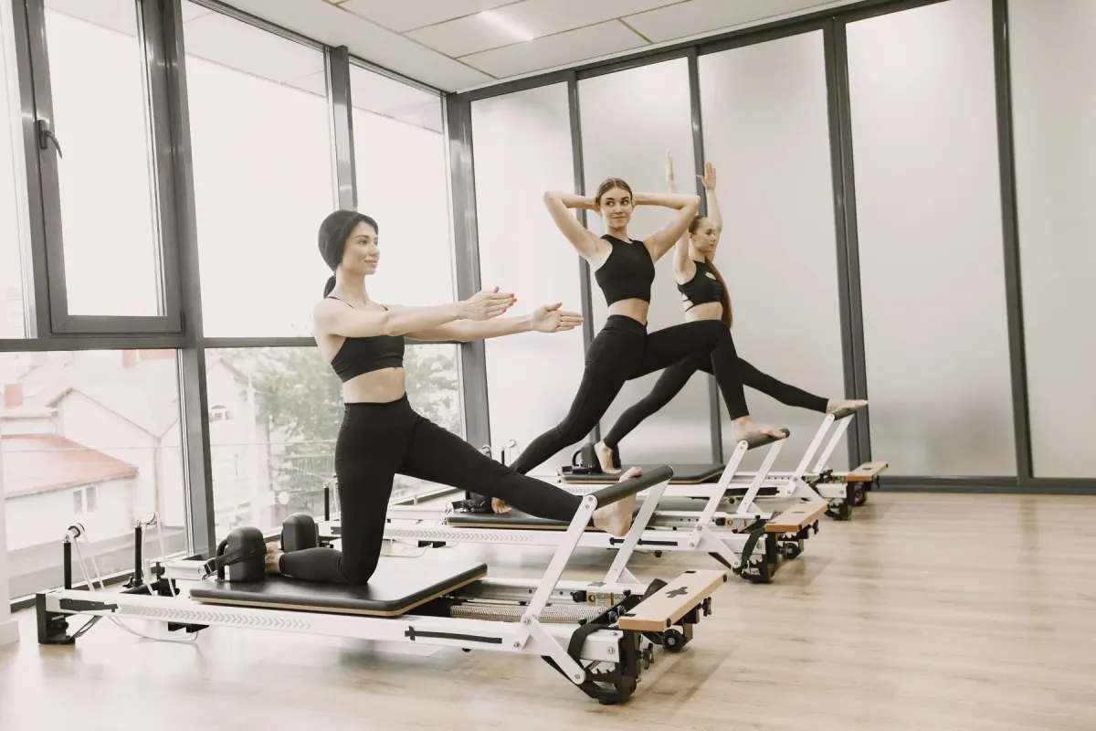 Drei Frauen trainieren auf Pilates-Reformern in einem hellen Studio